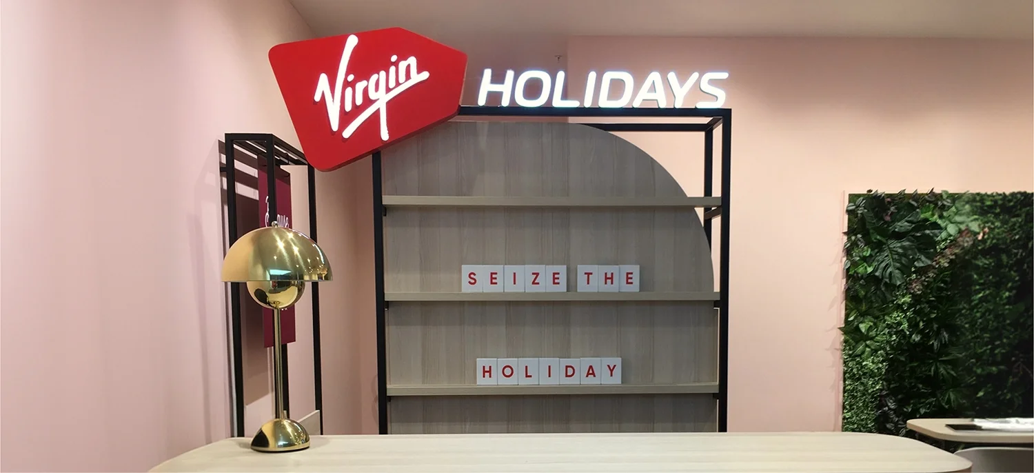 Virgin Holidays Bournemouth Next store with an illuminated logo display shelving and a plant wall