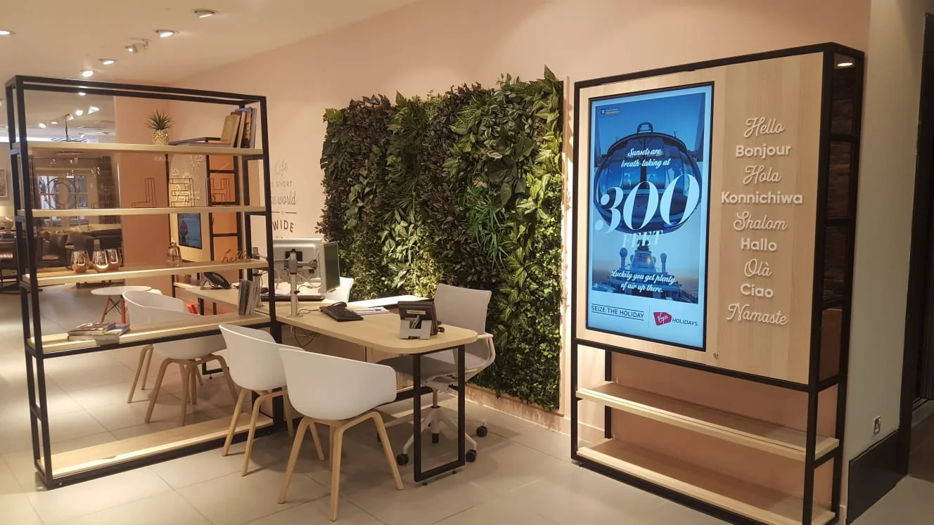 Virgin Holidays Shoreham Next consultation area with desk seating a green wall and a large digital poster