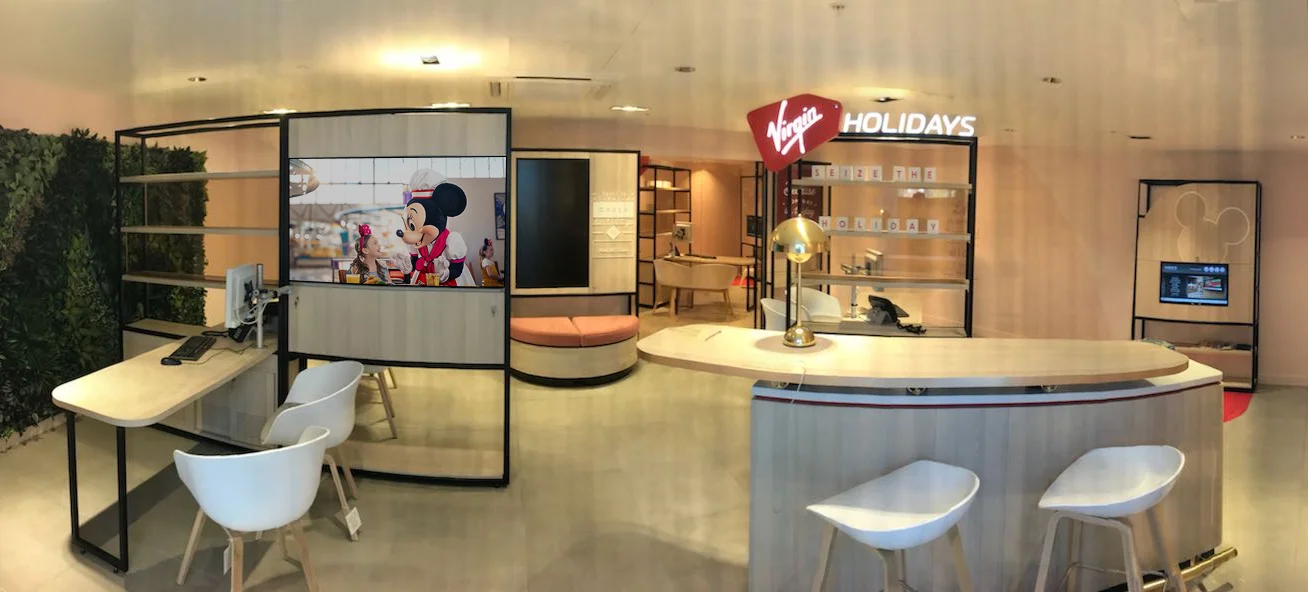 Virgin Holidays Southampton Next store with a curved reception desk consultation seating and a Disney display screen