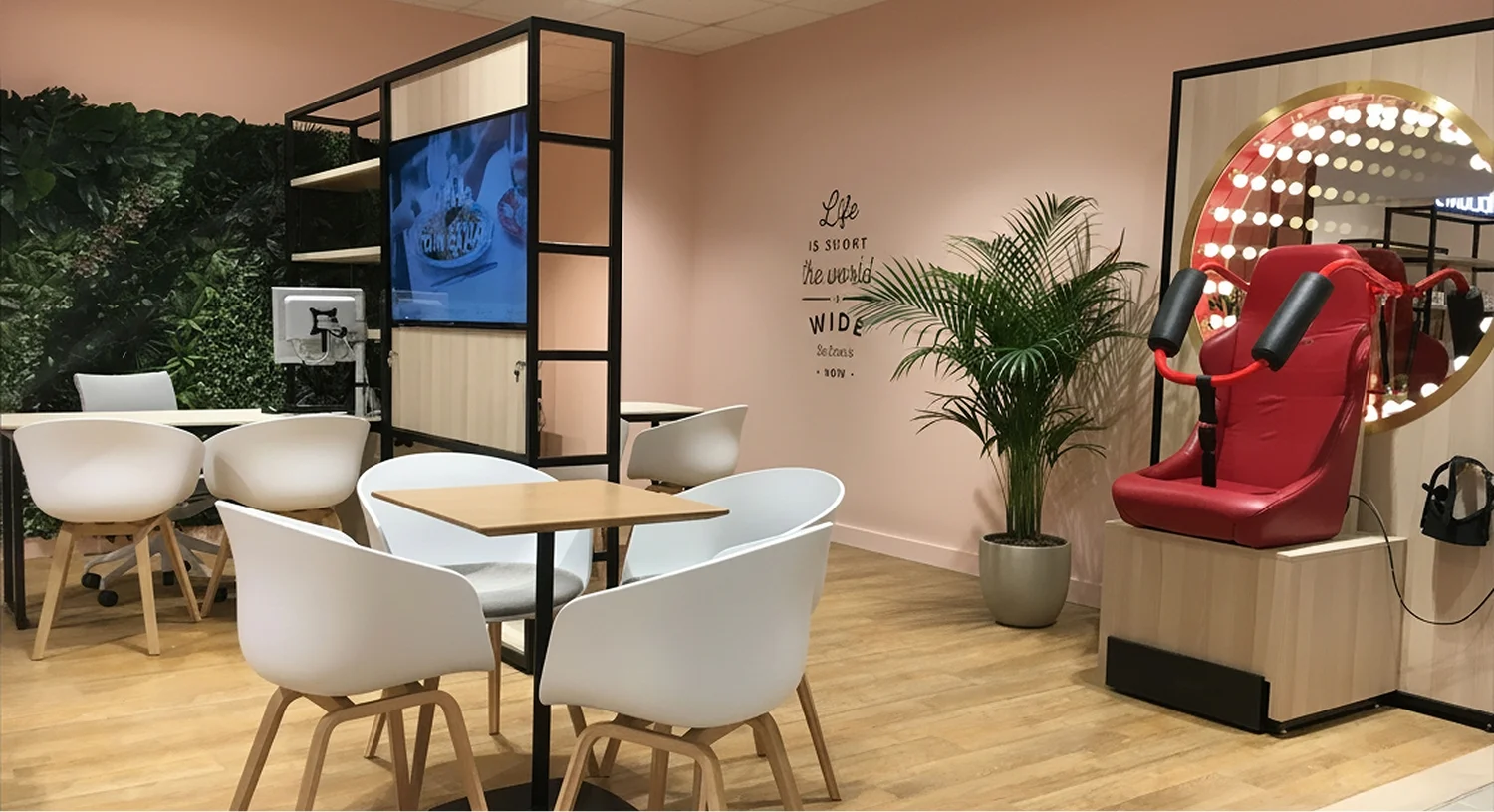 Virgin Holidays Manchester Next seating area with consultation tables a green wall a TV screen and red display seats