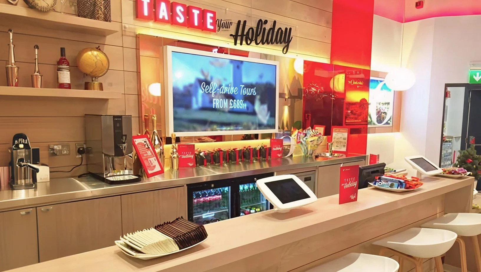 Virgin Holidays Vroom Lakeside refreshment bar with a coffee machine a large screen and Taste your Holiday signage