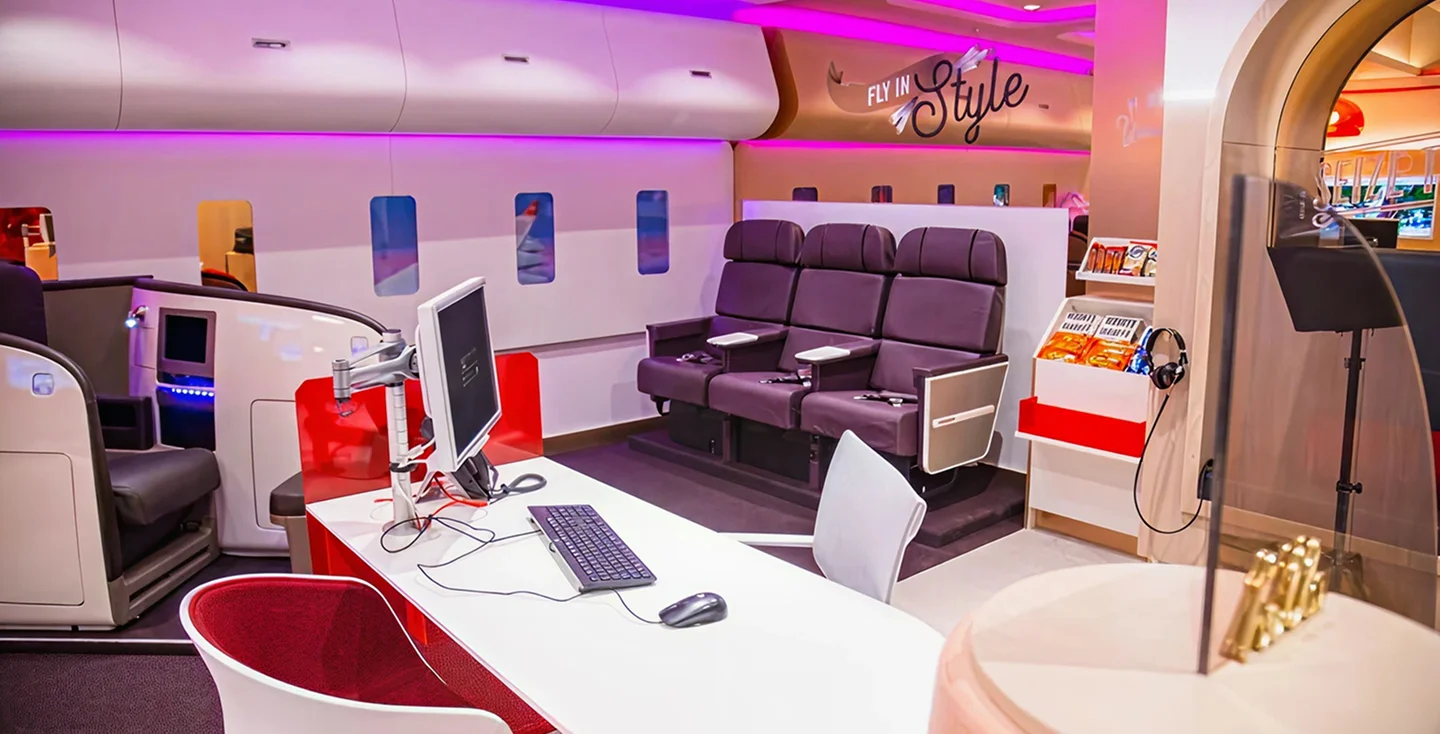 Virgin Holidays Vroom Norwich Chapelfield consultation area styled like an aircraft cabin with plane windows purple seats and a desk